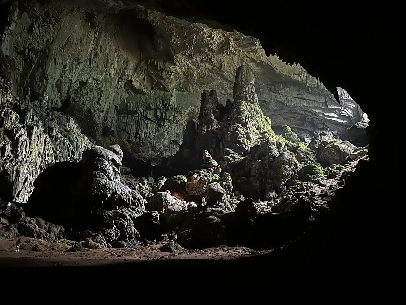 stalactite columns lit by diffused light inside a limestone cave