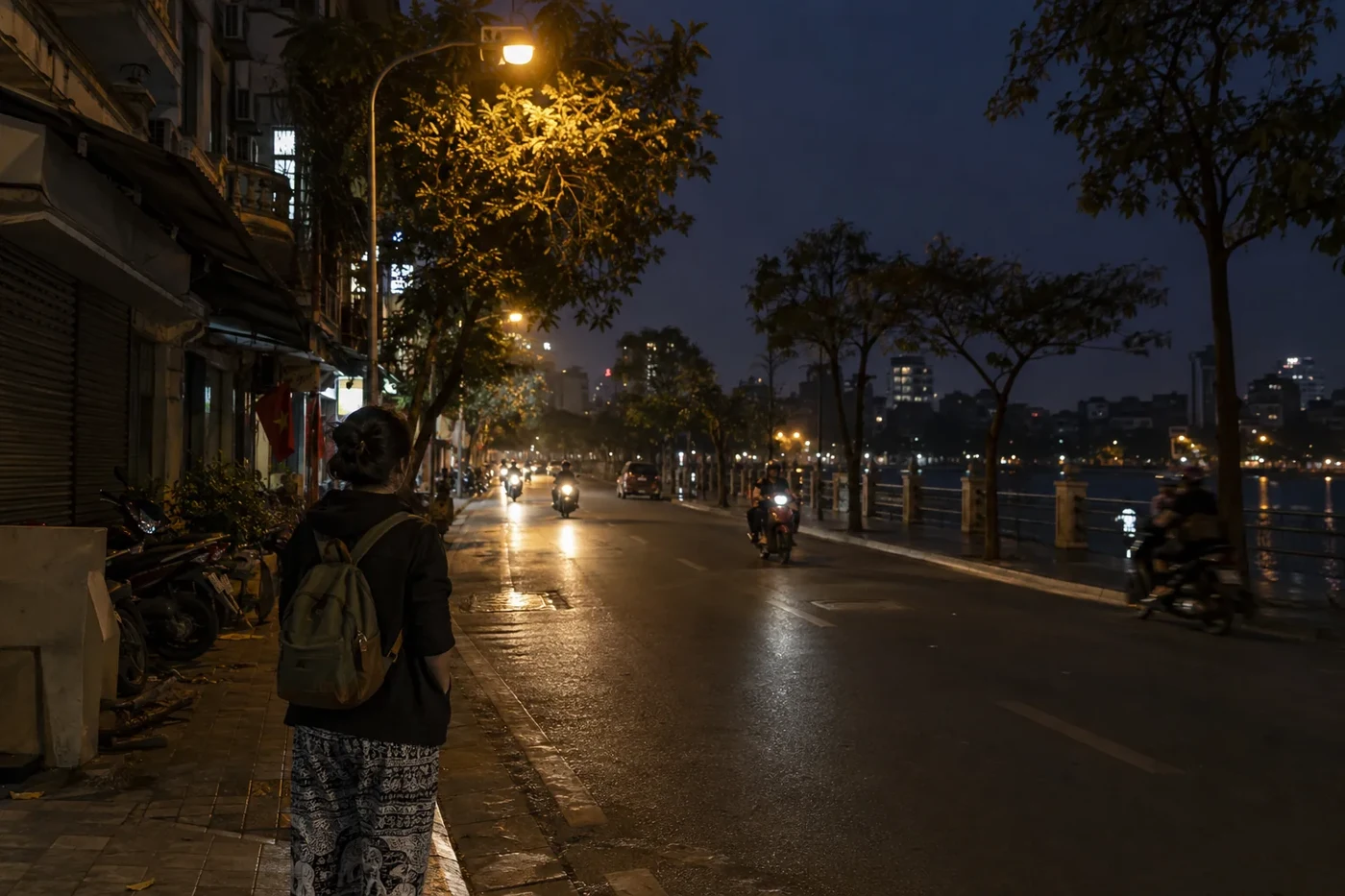 Traveler with a backpack on a dark street by the water before dawn
