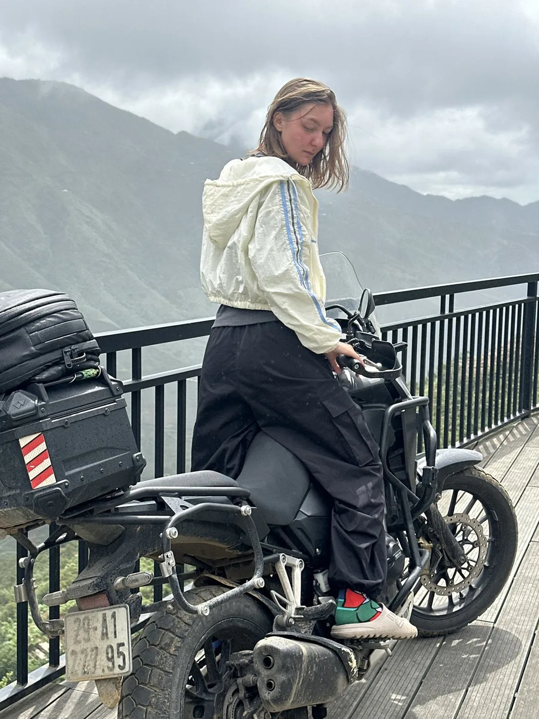 Woman getting on a motorbike at a misty mountain viewpoint in Ha Giang