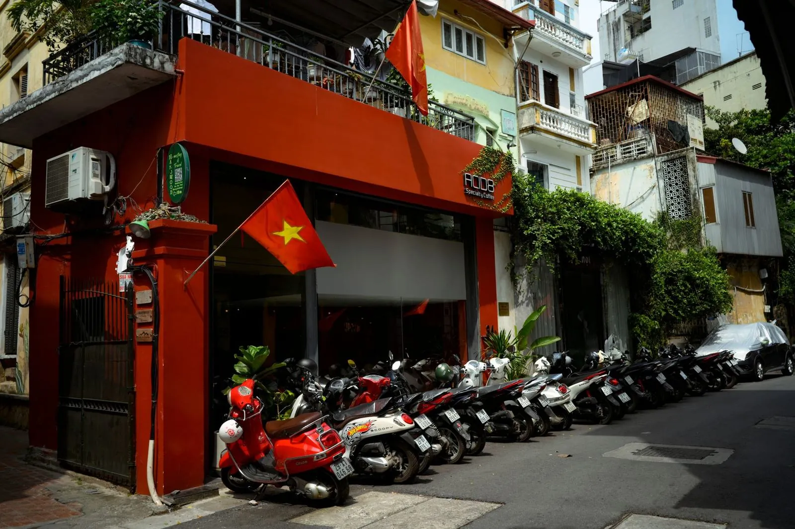 Row of scooters and motorbikes parked along a Hanoi street outside a coffee shop