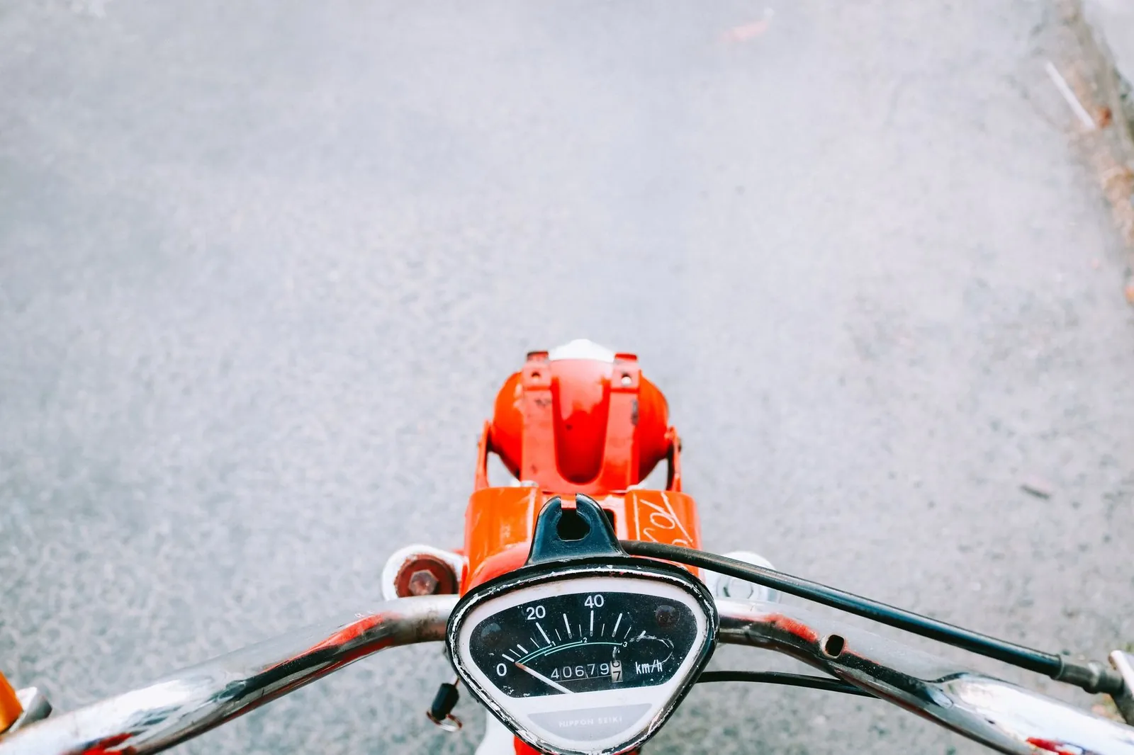 First-person view over the handlebars and speedometer of a motorbike on an open road
