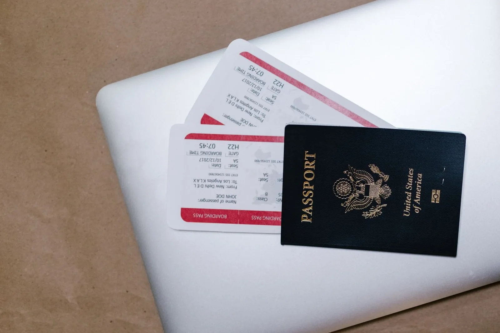 A passport and boarding passes resting on a laptop, symbolizing travel paperwork
