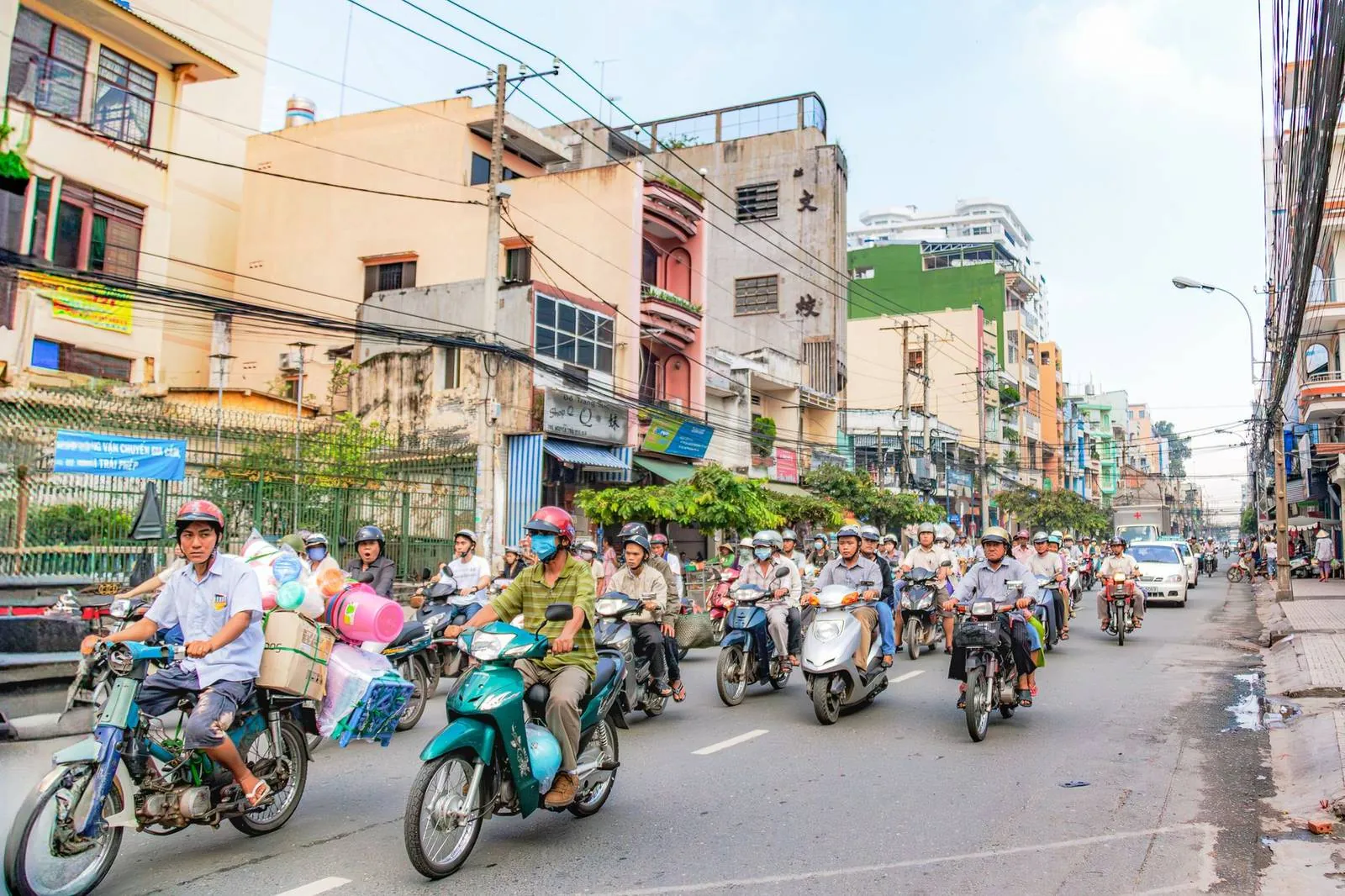 Motorbikes and scooters riding down a busy street lined with shops in Vietnam