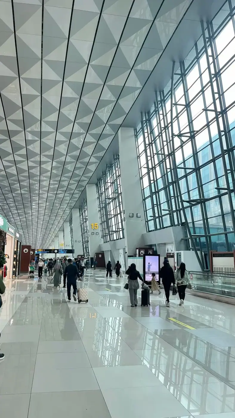 Travelers pulling luggage through a modern airport terminal