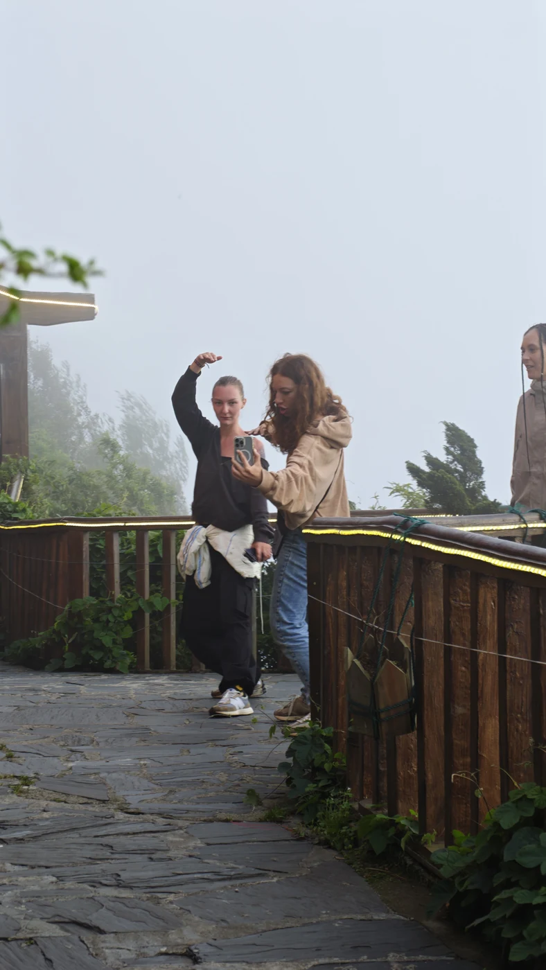 Two travelers taking a selfie on a foggy mountain viewpoint in Sapa