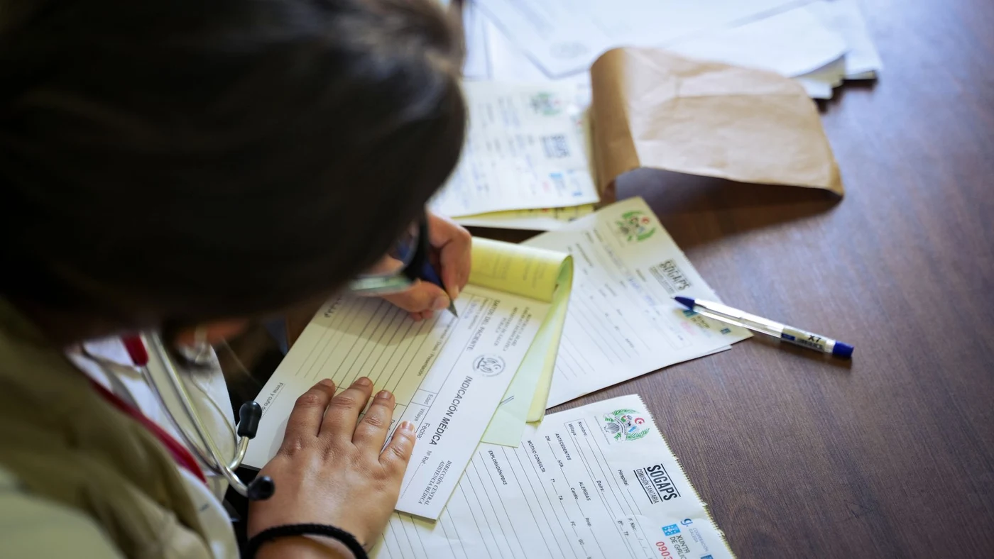 Doctor filling in a medical form at a desk