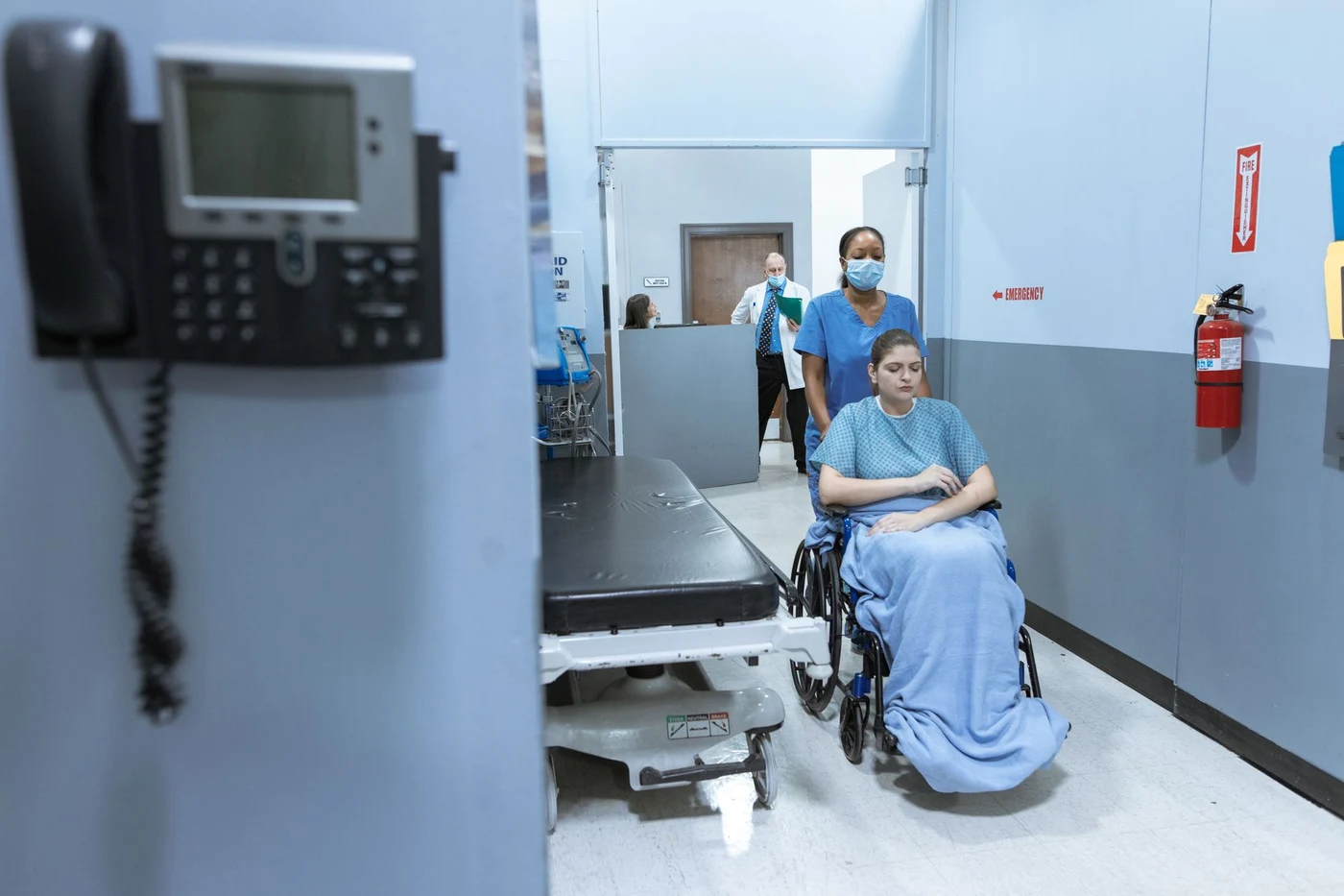 Nurse wheeling a patient along a hospital corridor