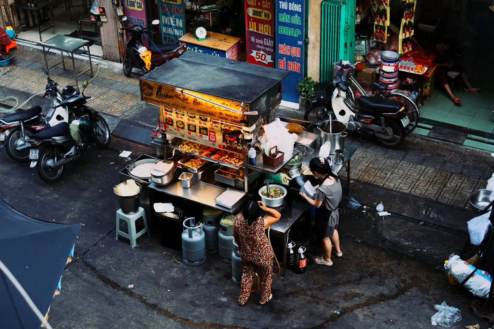 A Vietnamese street food stall with prices on a board and a QR code taped to the cart