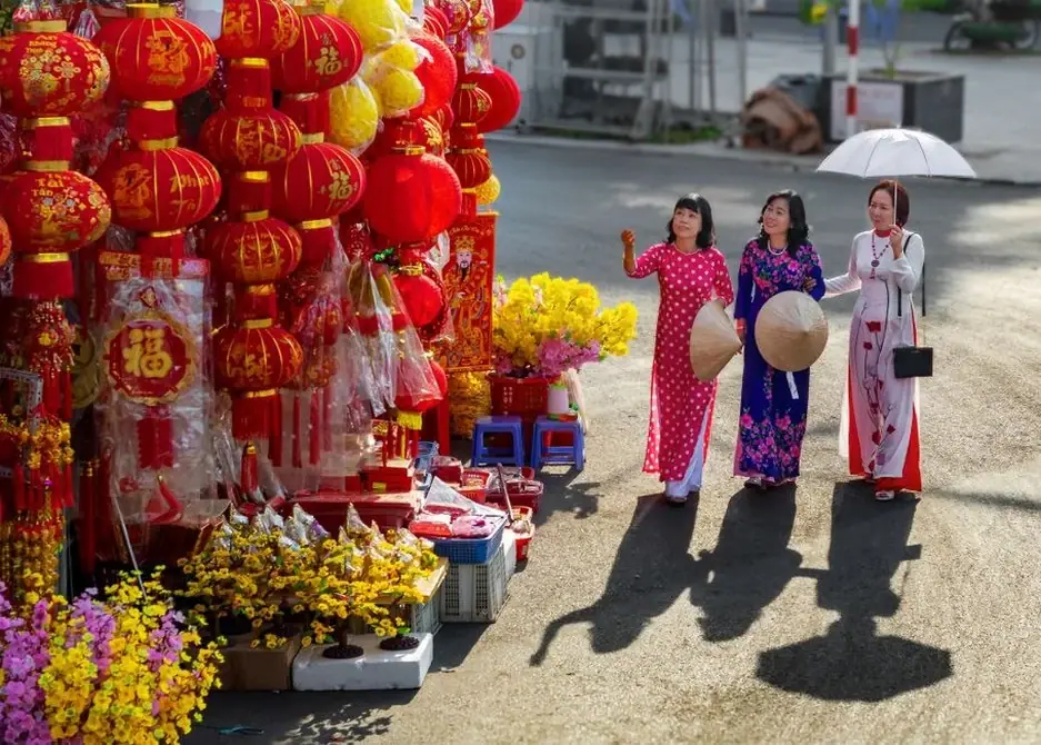 Women in traditional ao dai dresses shopping for lanterns Vietnam