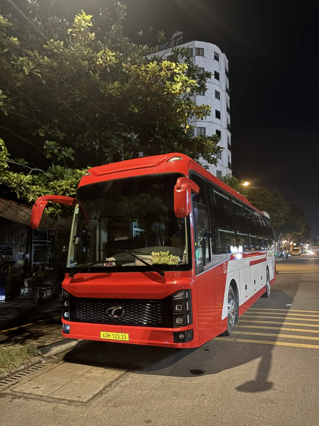 Sleeper bus parked roadside at night with headlights on
