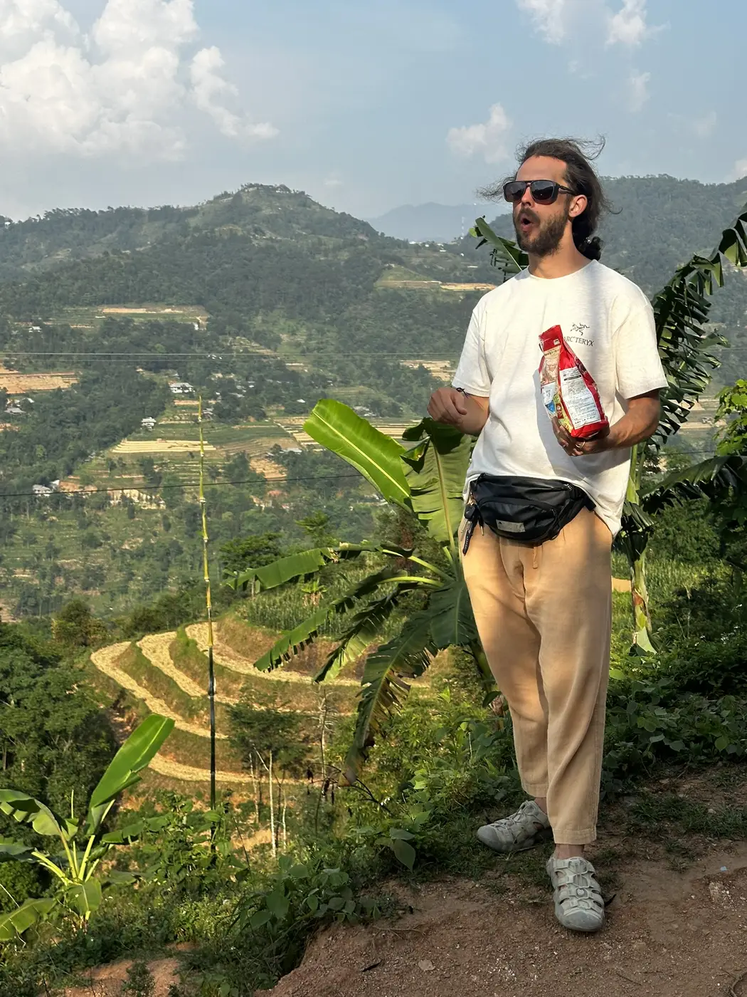 Traveler standing on a ridge above layered green rice terraces