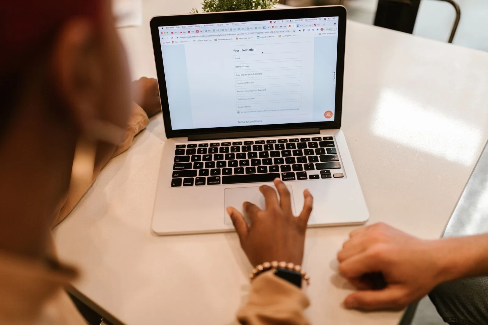 Two people filling out an online application form on a laptop