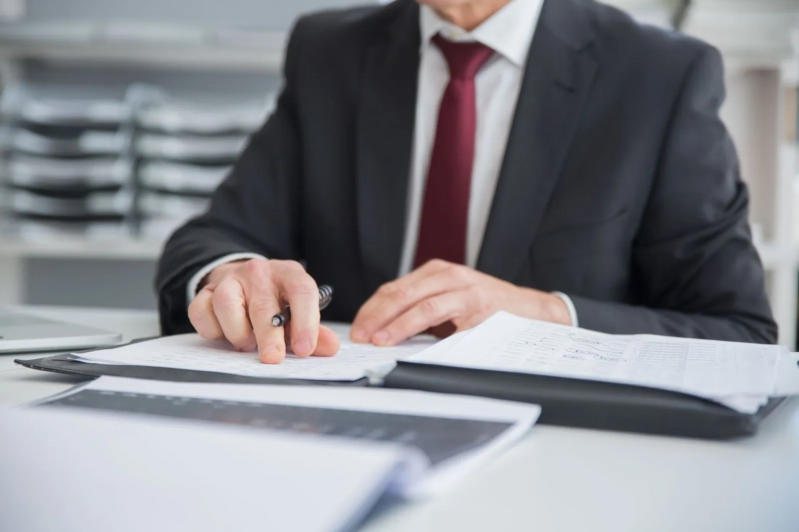 Close-up of a businessman reviewing paperwork with a pen at a desk