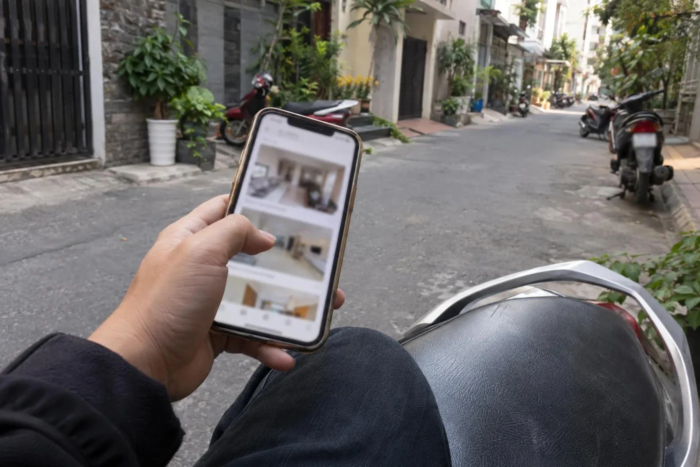 Hand holding a phone with apartment listings on a narrow street