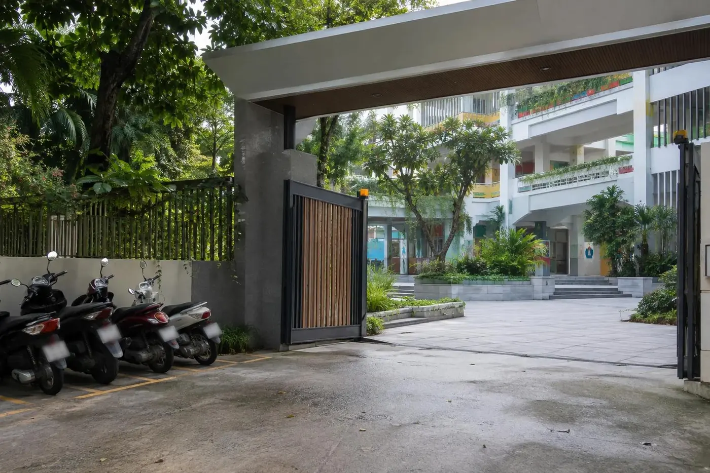 School courtyard gate in the morning with scooters parked outside