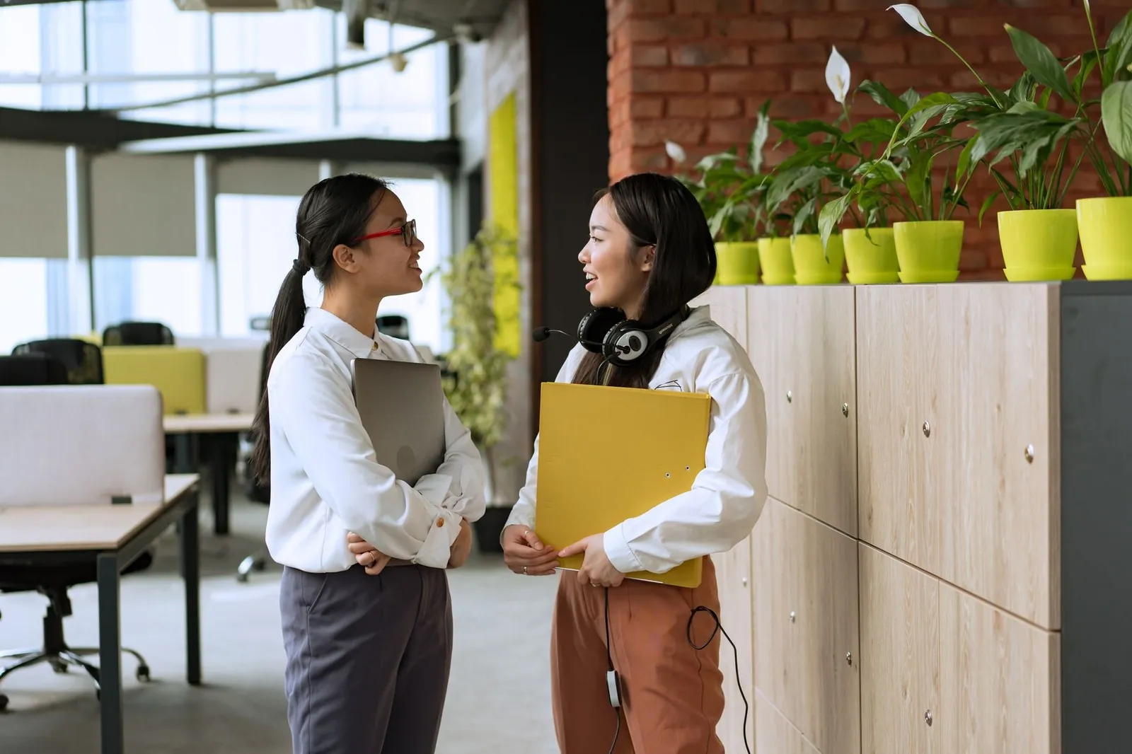 Two Vietnamese office colleagues talking in a coworking space