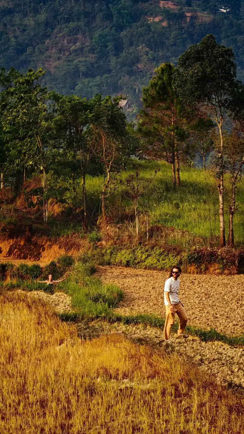 Two travelers walking through a golden rice field in the Vietnamese mountains
