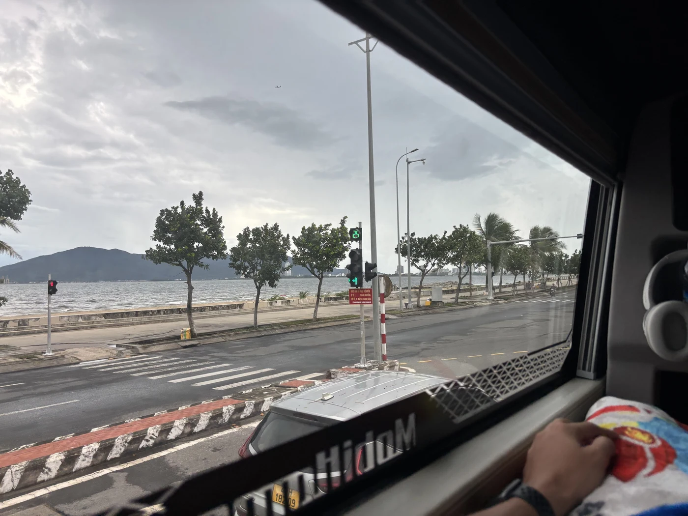 View from a sleeper bus window over the coastal road toward the sea