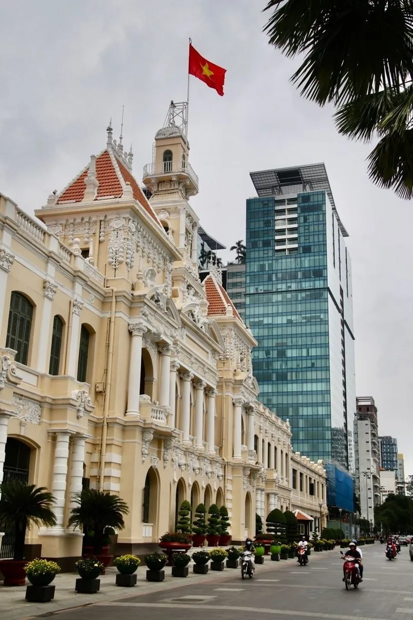 historic city hall building against a skyscraper in Ho Chi Minh City business district