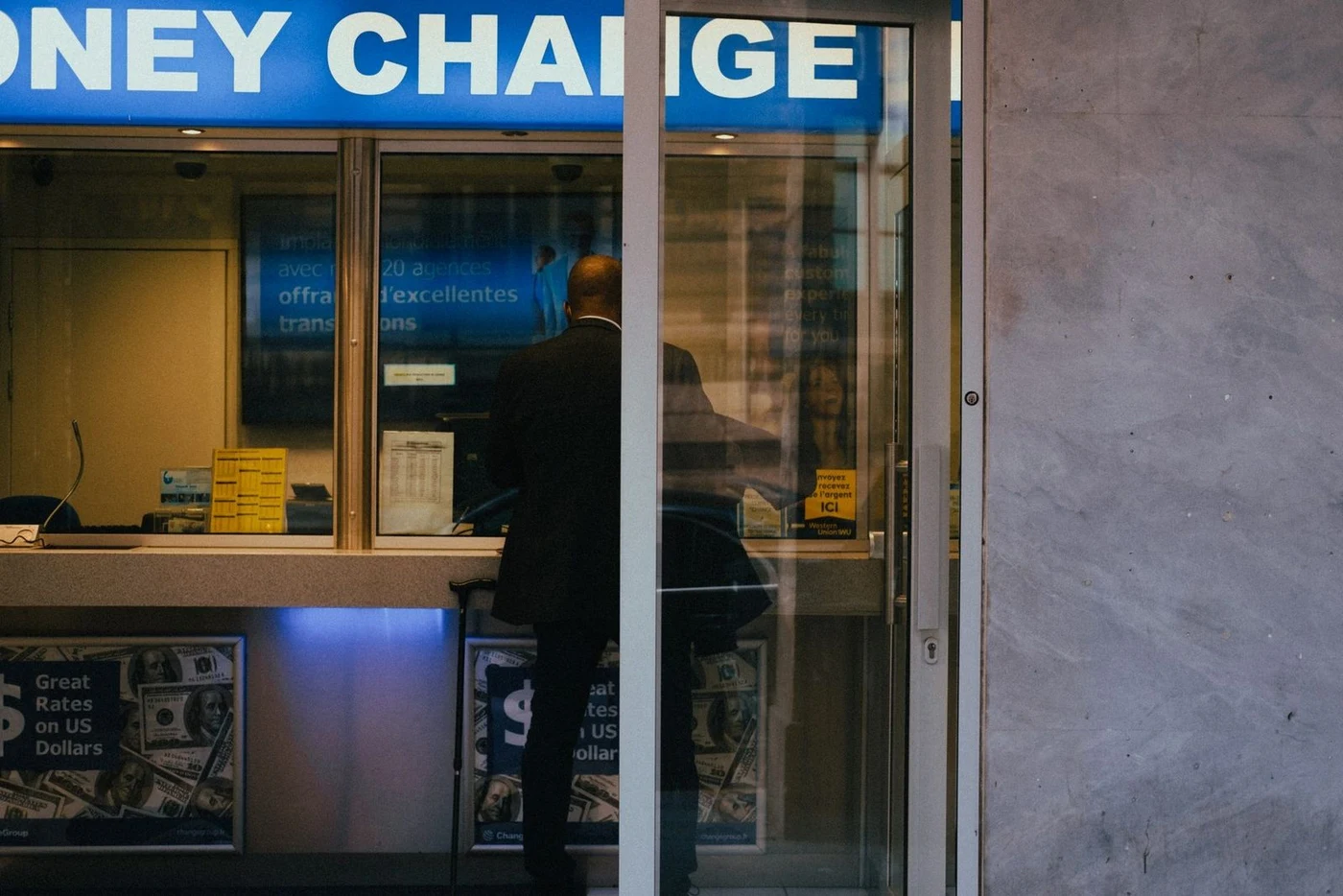 Man standing at a currency exchange window with a rate board