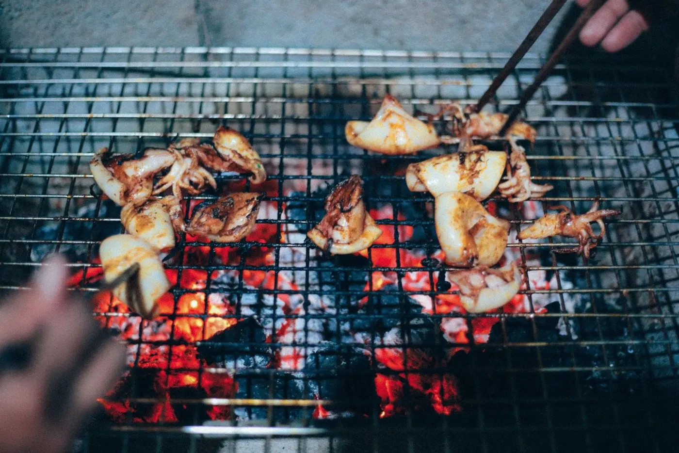 Squid grilling over coals at a street food stall