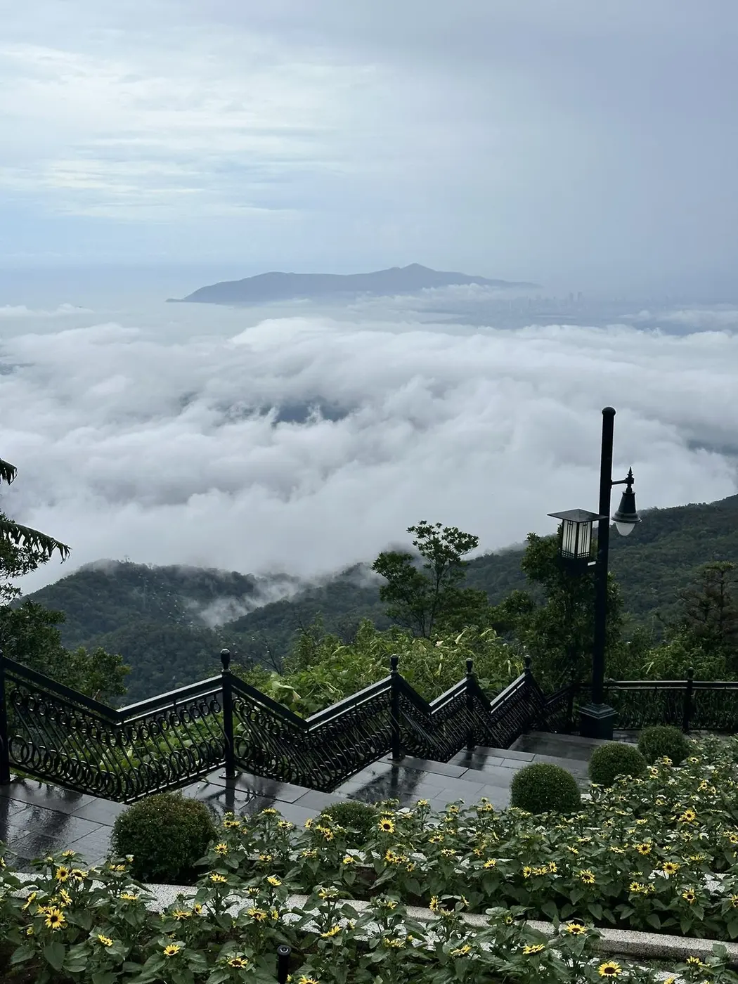 Stairs and flower beds above a sea of clouds with the Son Tra peninsula far away