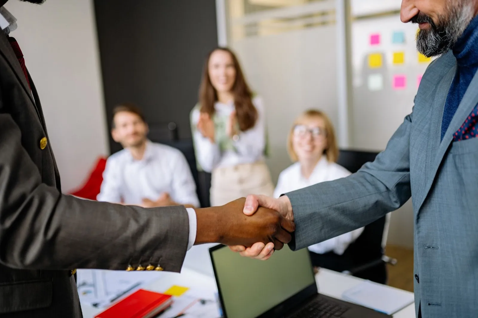 Business colleagues applauding after a handshake agreement in a meeting room